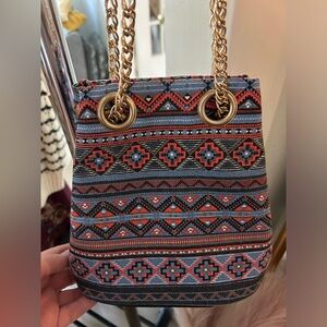 Multi pattern cinch purse. Never used, new with tags. Gold chain strap.